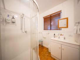 A bathroom with a shower, sink, and storage at Darling on Dorizac - Te Anau