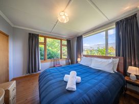 A bedroom with a bed and windows at Darling on Dorizac - Te Anau