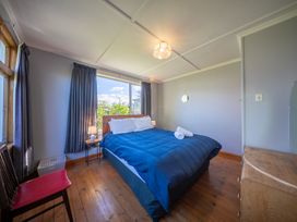 A bedroom with a bed, table, lamp and window at Darling on Dorizac - Te Anau Holiday Home Te Anau