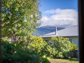 View of a house and mountain through trees at Darling on Dorizac - Te Anau