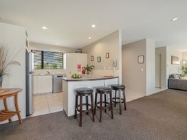 A kitchen with a counter, bar stools, and a refrigerator at Vintners - Renwick Holiday Home in Blenheim