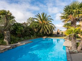 An outdoor area with a swimming pool and palm trees at La Belle Retreat - Ruakaka Holiday Apartment, Ruakaka