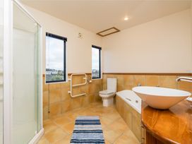 A bathroom with a shower, toilet, and bathtub at La Belle Retreat - Ruakaka Holiday Apartment Ruakaka