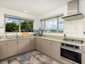 A kitchen with cabinets, a sink, stove, and windows at Bay Heights Bach - Bay Of Islands Retreat Kaitaia