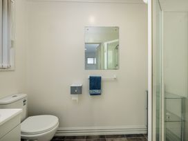 A bathroom with a toilet, mirror, and towel at Bay Heights Bach - Bay Of Islands Retreat, Kaitaia