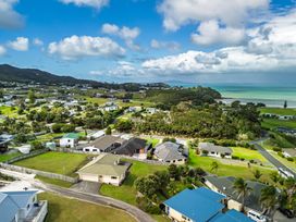 An aerial view of houses and green land near the ocean at Bay Heights Bach - Bay Of Islands Retreat, Kaitaia