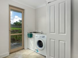 A laundry room with a washing machine and a door at Bay Heights Bach - Bay Of Islands Retreat Kaitaia