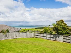 A garden with grass and a fence overlooking water at Bay Heights Bach - Bay Of Islands Retreat Kaitaia