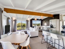 A living room with a dining area and kitchen at Raglan Holiday Home in Raglan