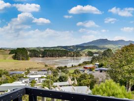 A view of houses and lake with hills in the background at Raglan Holiday Home in Raglan