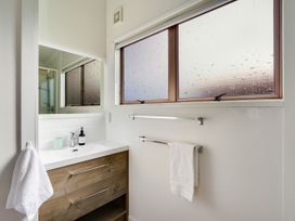 A bathroom with a sink and mirror at Raglan Holiday Home in Raglan