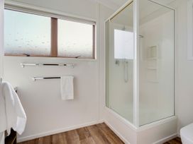 A bathroom featuring a shower and towel rack at Raglan Holiday Home in Raglan