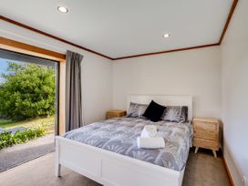 A bedroom with a bed and nightstand at Raglan Holiday Home in Raglan