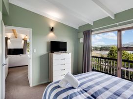 A bedroom with a bed and television at Raglan Holiday Home in Raglan