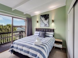 A bedroom with a bed and artwork at Raglan Holiday Home in Raglan