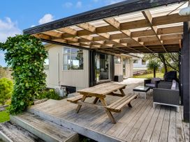 An outdoor deck with a wooden table and chairs at Raglan Holiday Home in Raglan