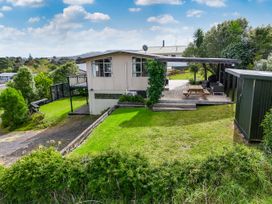 A house with a deck and garden at Raglan Holiday Home in Raglan