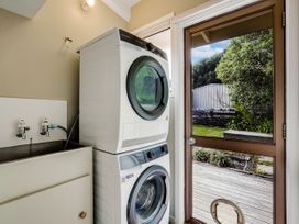 A laundry room with a washer and dryer and a sink at Raglan Holiday Home in Raglan