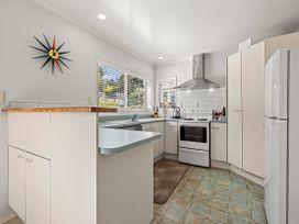 A kitchen with cabinets and appliances at Raglan Holiday Home in Raglan
