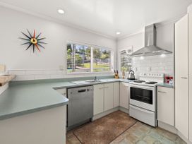 A kitchen with an oven, dishwasher, and sink at Raglan Holiday Home in Raglan