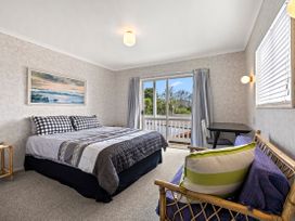 A bedroom with a bed and window at Raglan Holiday Home in Raglan