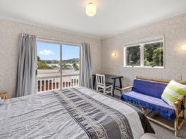 A bedroom with a bed and a table at Raglan Holiday Home in Raglan