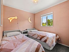 A bedroom with two beds and decorative lights at Raglan Holiday Home in Raglan