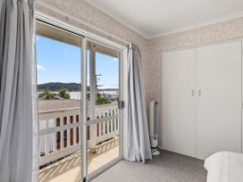 A bedroom with a window and wardrobe at Raglan Holiday Home in Raglan