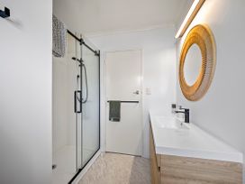 A bathroom with a shower and sink at Raglan Holiday Home in Raglan