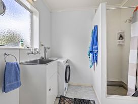 A laundry room with a washing machine and sink at Raglan Holiday Home Raglan