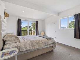 A bedroom with a bed and window at Sundowners - Mangawhai Heads Holiday Home, Mangawhai