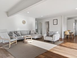 A living room with a sofa and armchair at Sundowners - Mangawhai Heads Holiday Home in Mangawhai