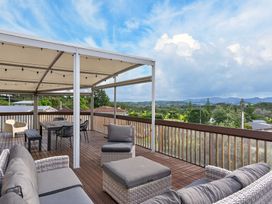 An outdoor deck with seating and a table at Sundowners - Mangawhai Heads Holiday Home Mangawhai