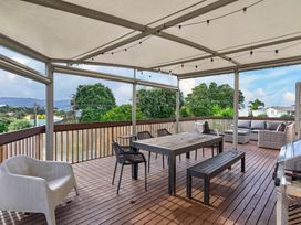 An outdoor patio with seating and a table at Sundowners - Mangawhai Heads Holiday Home in Mangawhai
