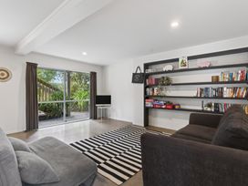 A living room with a sofa and a bookshelf at Sundowners - Mangawhai Heads Holiday Home, Mangawhai