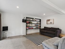 A living room with a sofa and bookshelf at Sundowners - Mangawhai Heads Holiday Home in Mangawhai