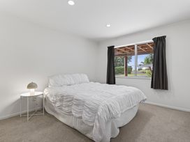 A bedroom with a bed and a bedside table at Sundowners - Mangawhai Heads Holiday Home in Mangawhai