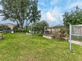 A garden with a tree and clothesline at Sundowners - Mangawhai Heads Holiday Home in Mangawhai