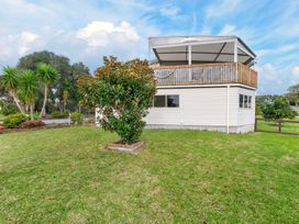 A house with a deck and garden at Sundowners - Mangawhai Heads Holiday Home Mangawhai