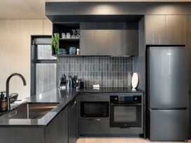 A kitchen with a sink, refrigerator, oven, and cabinets at Stonepeak - Queenstown Holiday Home in Queenstown
