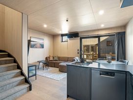 A living room with a sofa and kitchen area at Stonepeak - Queenstown Holiday Home in Queenstown