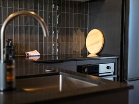A kitchen with a sink, faucet, cutting board and stove at Stonepeak - Queenstown Holiday Home in Queenstown