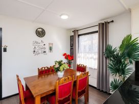 A dining room with a wooden table and eight chairs at Dannevirke Lodge in Dannevirke
