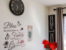 A living room with wall decor and a clock at Dannevirke Lodge - Dannevirke