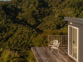 A deck with a chair and a sliding door at Little Tui Ridge - Coromandel Holiday Home