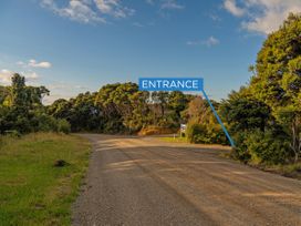 A road leading to an entrance sign with trees and grass in the background at Little Tui Ridge - Coromandel