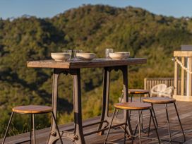 A table with bowls and glasses in an outdoor dining area at Little Tui Ridge - Coromandel