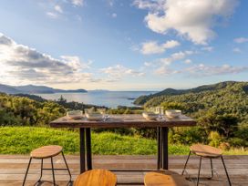 An outdoor dining area with a table and chairs overlooking the ocean at Little Tui Ridge - Coromandel