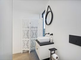 A bathroom with a sink and mirror at Little Tui Ridge - Coromandel Holiday Home
