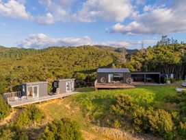 A cabin with a deck and outdoor seating at Little Tui Ridge - Coromandel